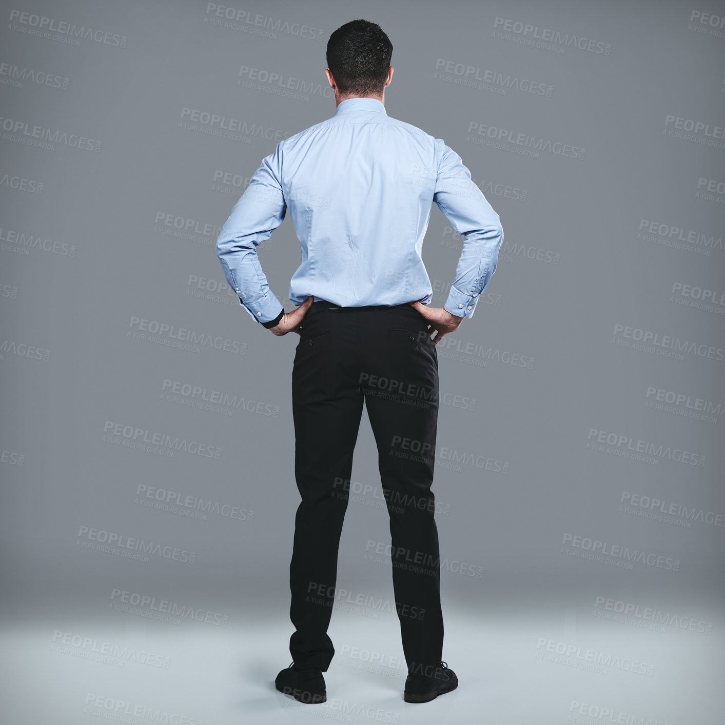 Buy stock photo Rearview studio shot of a young businessman standing against a grey background