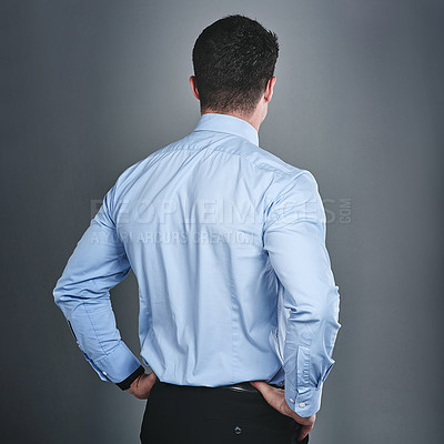 Buy stock photo Rearview studio shot of a young businessman standing against a grey background