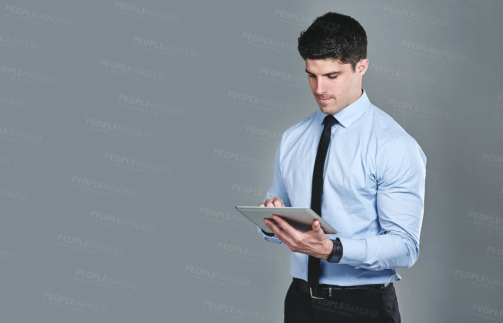Buy stock photo Studio shot of a young businessman using a digital tablet against a grey background