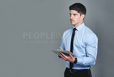 Buy stock photo Studio shot of a young businessman using a digital tablet against a grey background