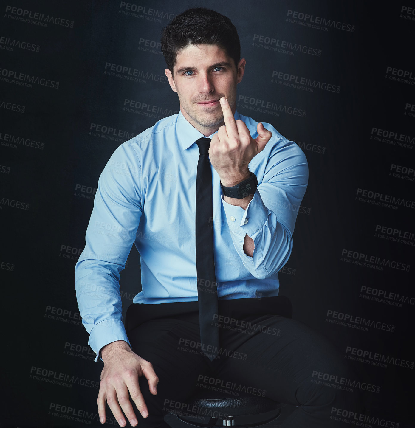 Buy stock photo Studio portrait of a young businessman showing the middle finger against a dark background