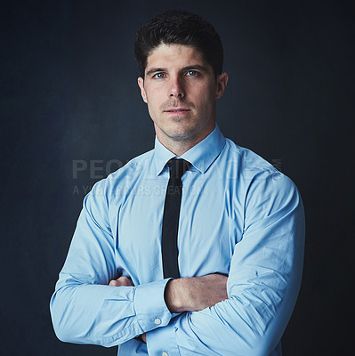 Buy stock photo Studio portrait of a young businessman posing against a dark background