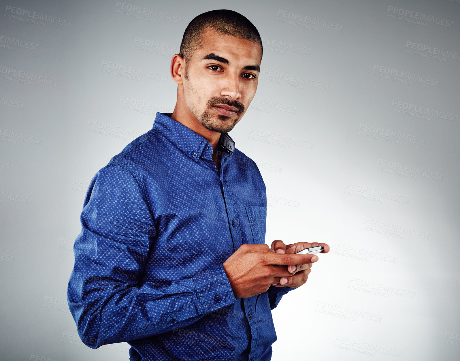 Buy stock photo Studio shot of a young businessman using his cellphone against a grey background