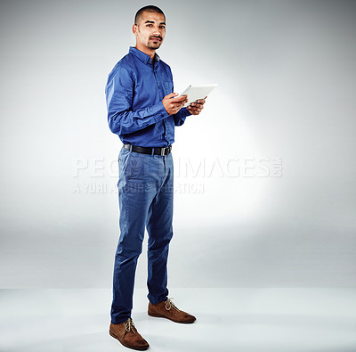 Buy stock photo Studio shot of a young businessman using his tablet against a grey background