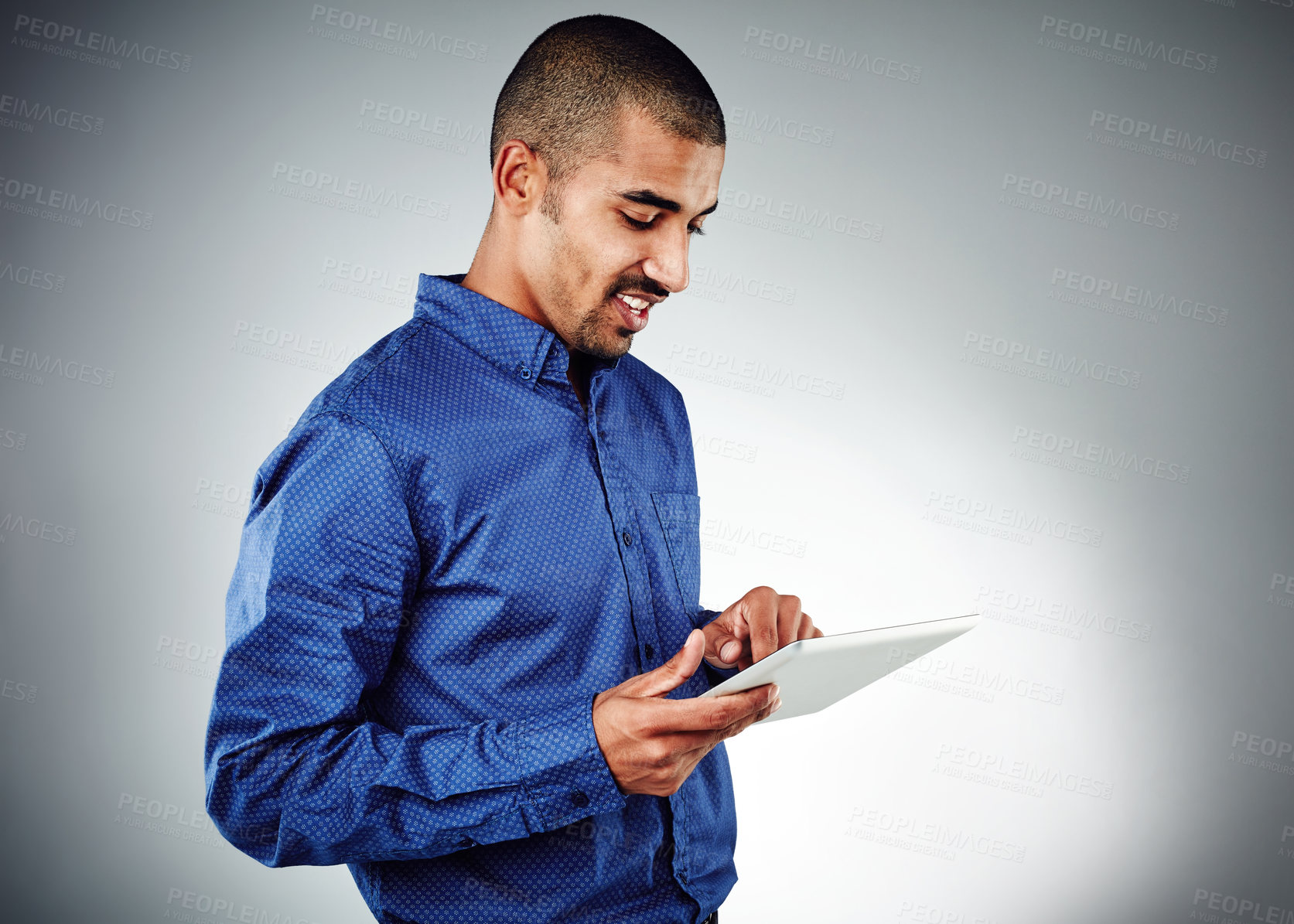 Buy stock photo Studio shot of a young businessman using his tablet against a grey background