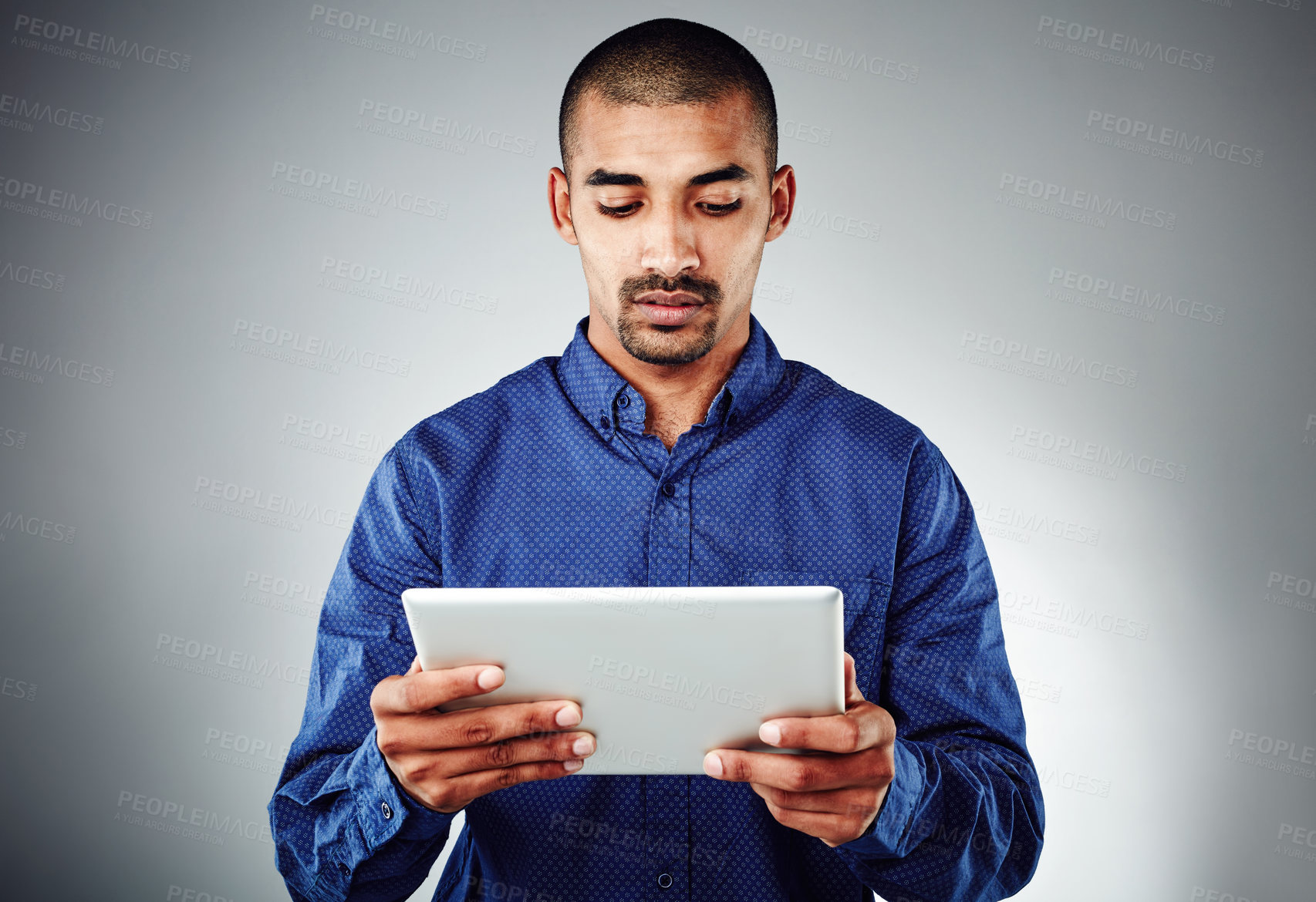 Buy stock photo Studio shot of a young businessman using his tablet against a grey background