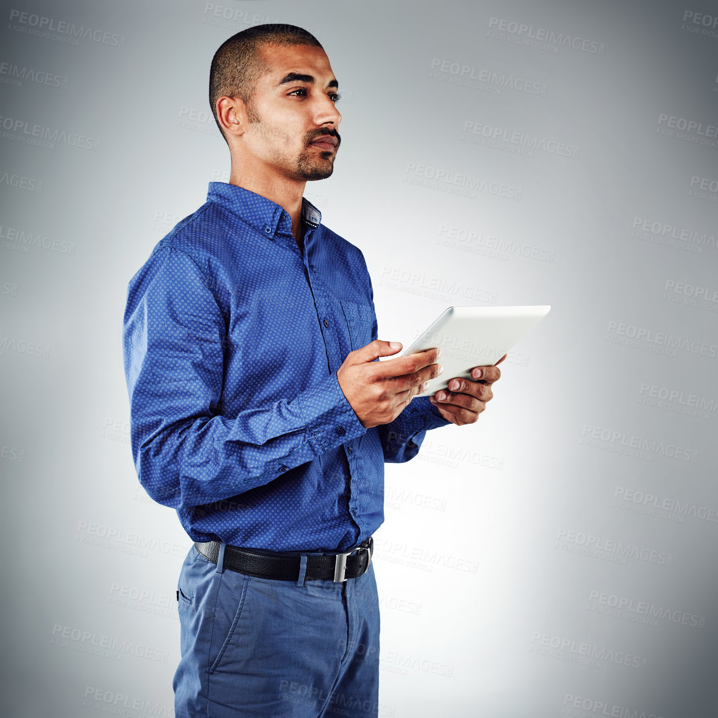 Buy stock photo Studio shot of a young businessman using his tablet against a grey background