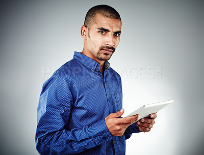 Buy stock photo Studio shot of a young businessman using his tablet against a grey background