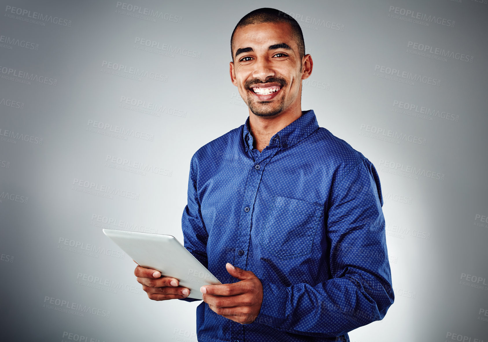 Buy stock photo Studio shot of a young businessman using his tablet against a grey background