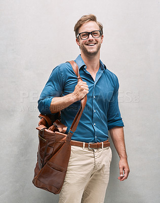 Buy stock photo Cropped portrait of a handsome young man posing with a bag in the studio