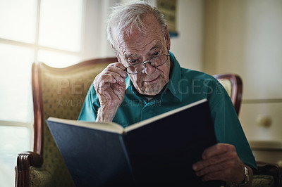 Buy stock photo Elderly man, novel and reading book in lounge, literature and language for learning in retirement. Old person, fiction and textbook for knowledge to relax in home, glasses and studying information