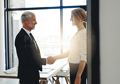 Buy stock photo Cropped shot of two businesspeople shaking hands while standing in the office