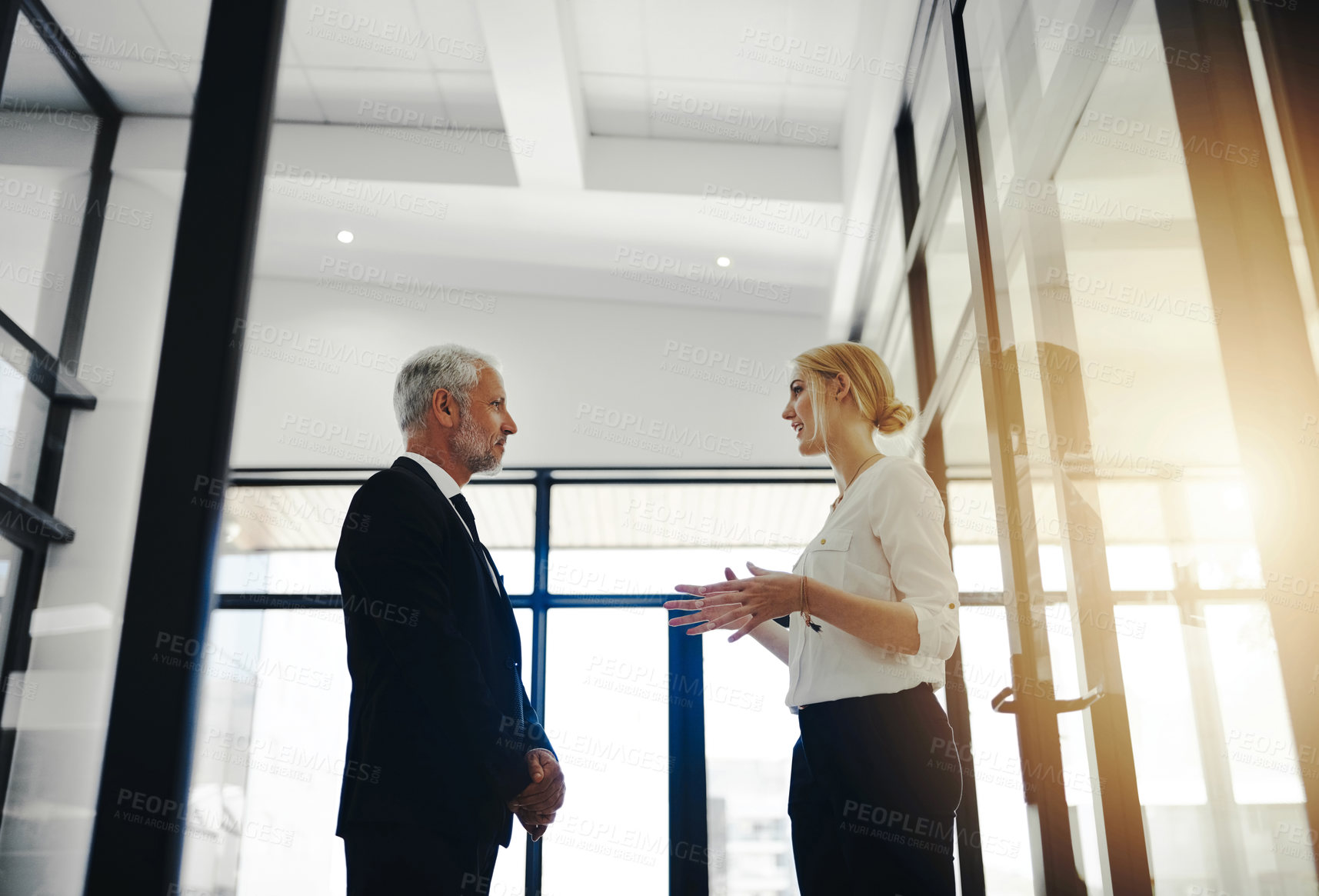 Buy stock photo Cropped shot of two businesspeople talking while standing in the office