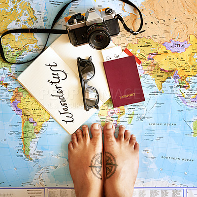Buy stock photo High angle shot of a young tourist's feet standing on a map with a notebook, camera and passport arranged on it