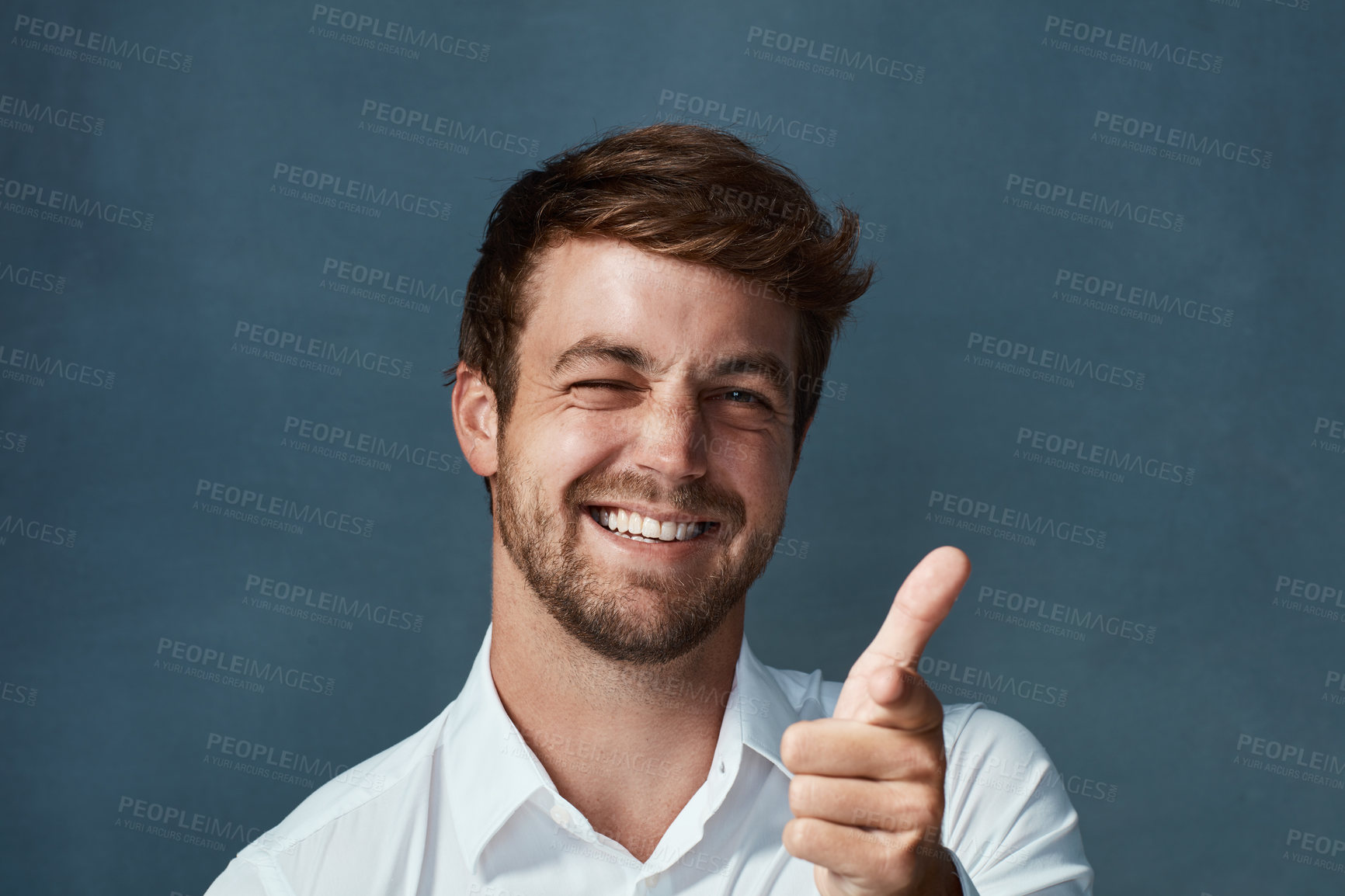 Buy stock photo Studio portrait of a handsome young man showing thumbs up against a dark background