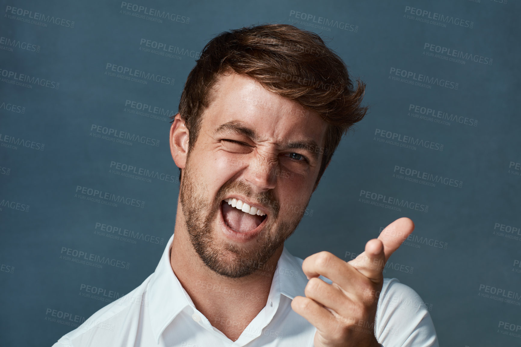 Buy stock photo Studio portrait of a handsome young man making a face against a dark background