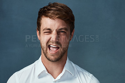 Buy stock photo Studio portrait of a handsome young man winking against a dark background
