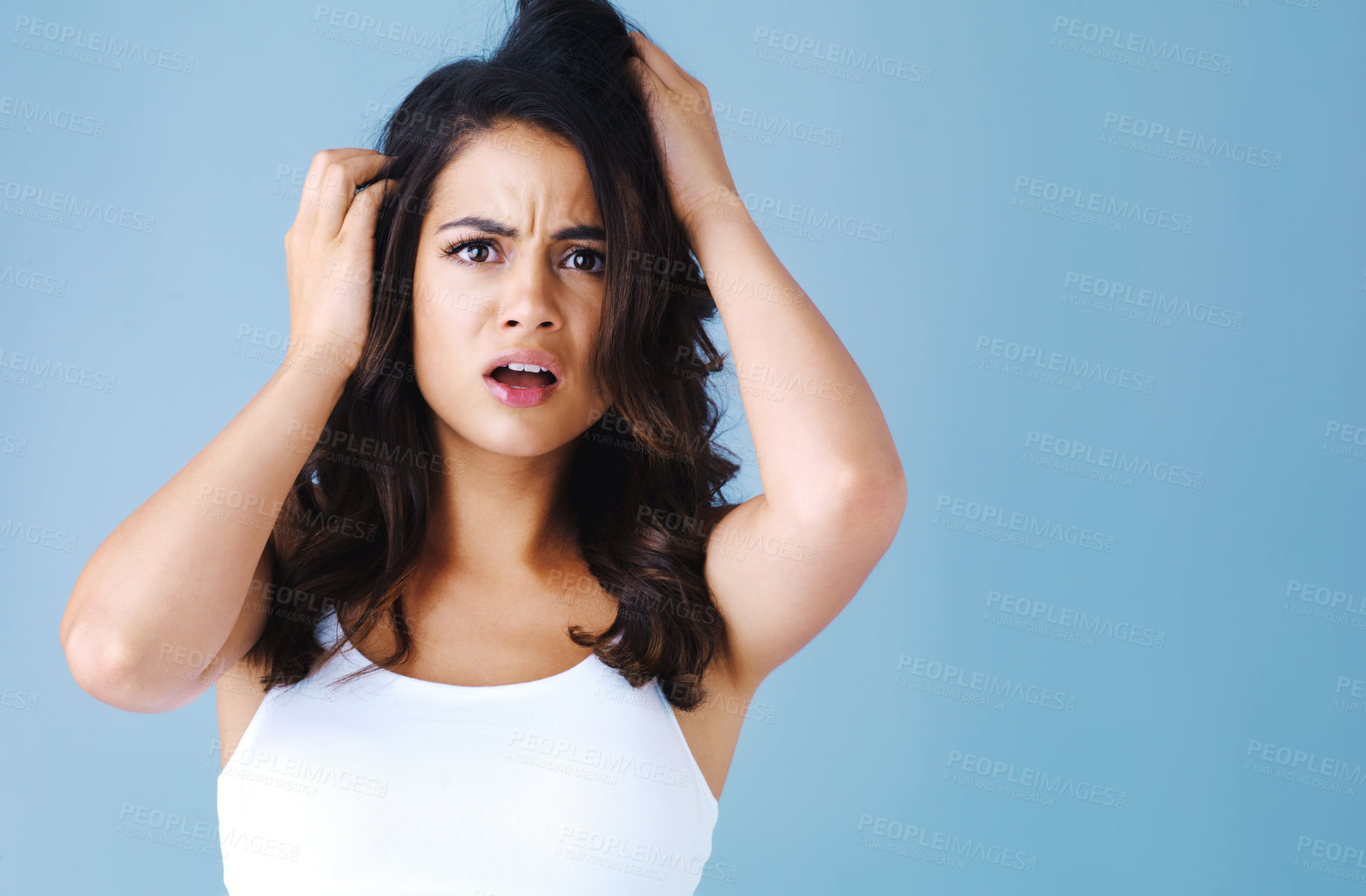 Buy stock photo Studio shot of an attractive young woman looking worried against a blue background