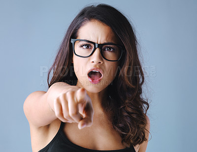 Buy stock photo Studio shot of an attractive young woman pointing and looking angry against a gray background