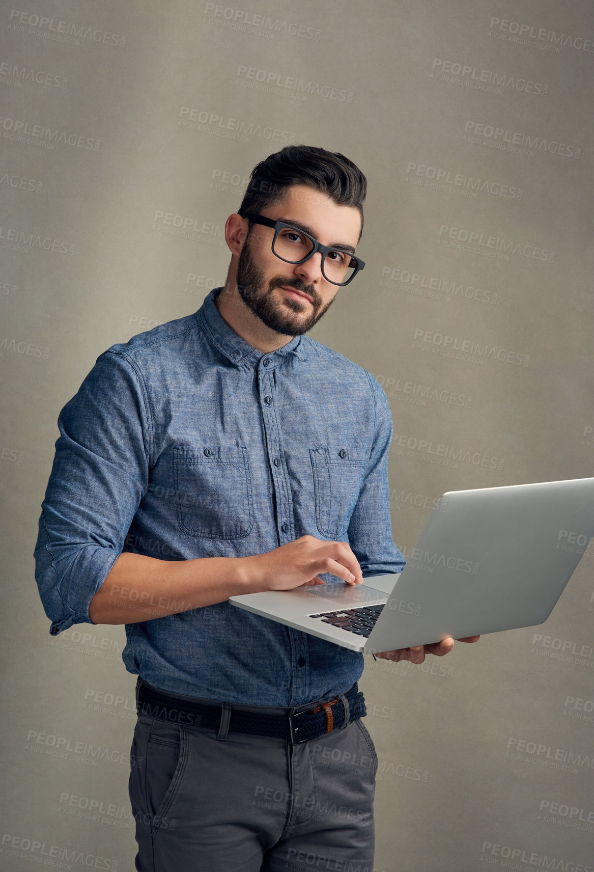 Buy stock photo Studio portrait of a handsome young man using a laptop against a grey background