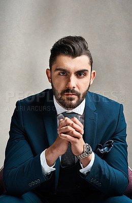 Buy stock photo Studio portrait of a stylishly dressed young businessman sitting on a chair against a grey background