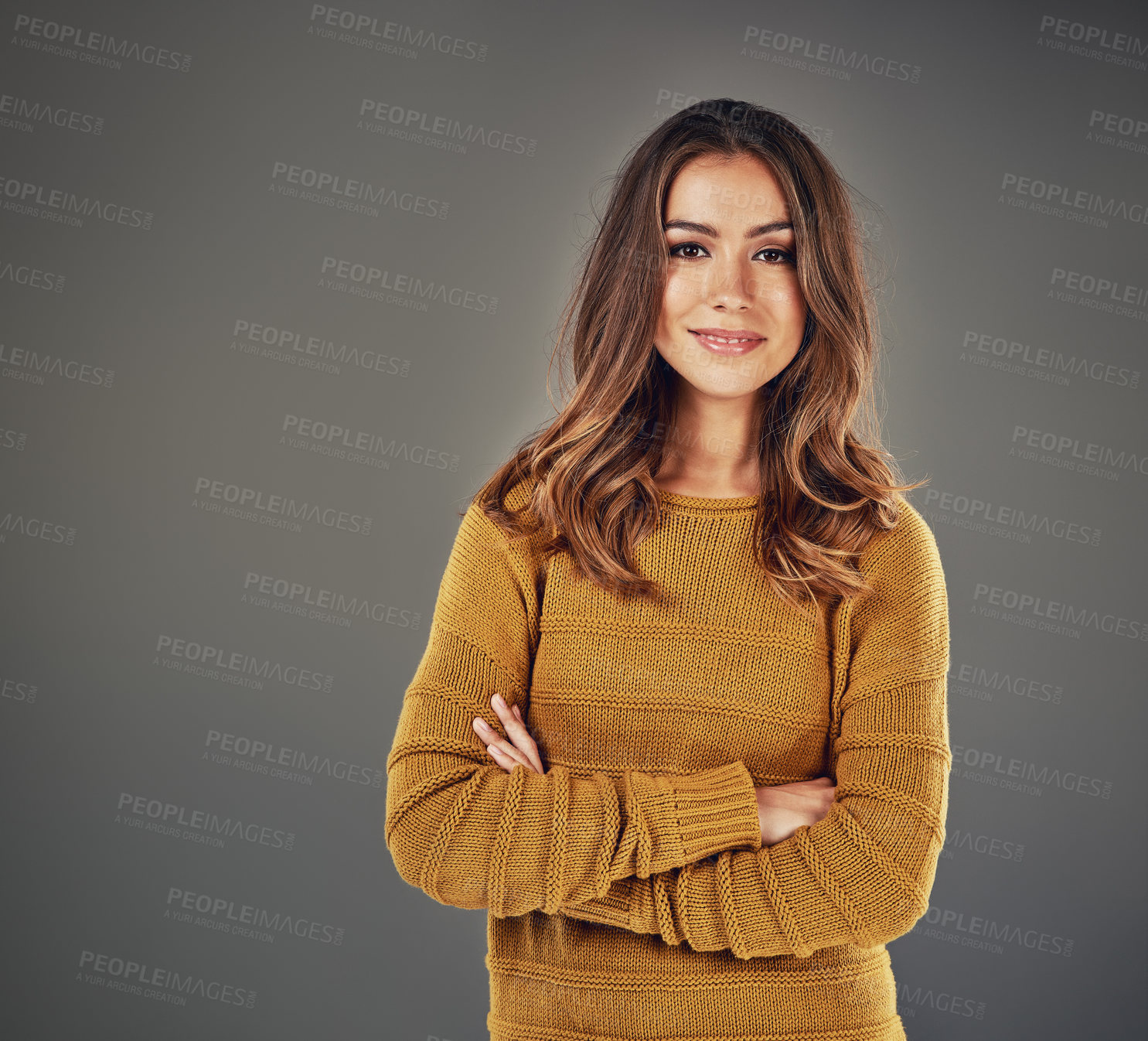 Buy stock photo Portrait of an attractive young woman standing with her arms folded against a grey background
