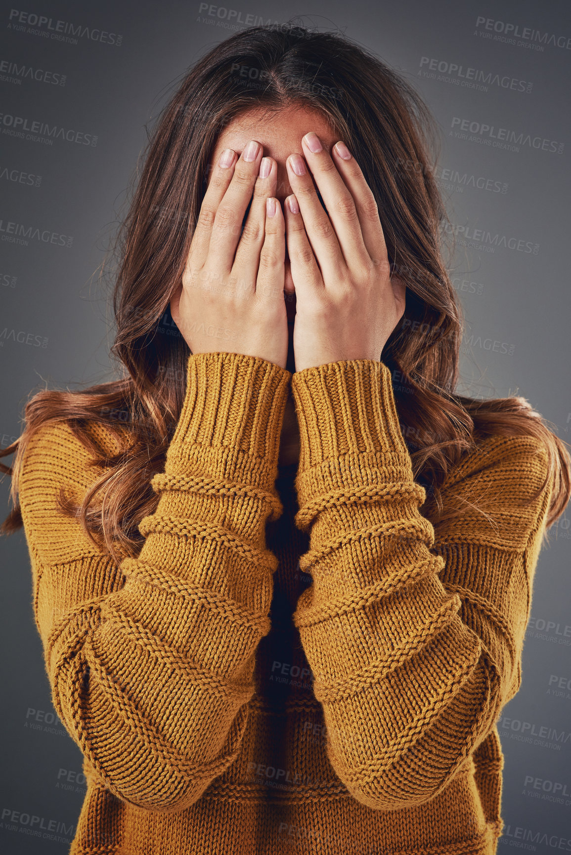 Buy stock photo Studio shot of a young woman covering her face against a grey background
