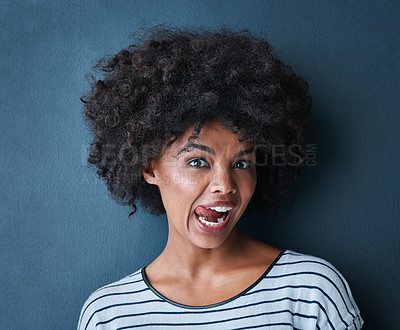 Buy stock photo Black woman, emoji and tongue with facial expression in studio for fun, relax and playful attitude on blue background. Lady, comic and goofy portrait with a funny face, crazy and personality isolated