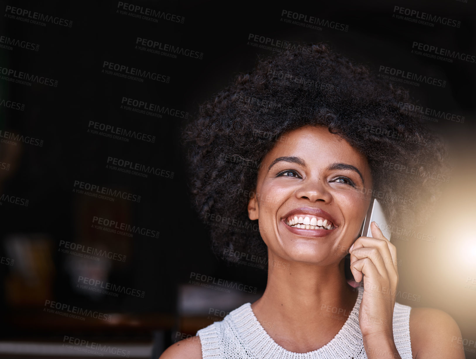 Buy stock photo Shot of a happy young business owner answering her phone while standing inside her coffee shop