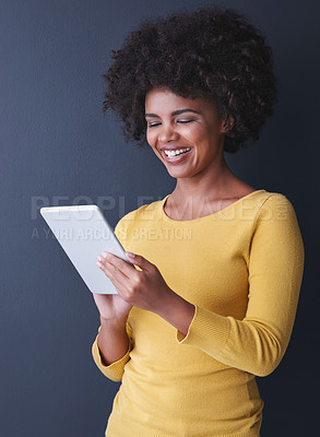 Buy stock photo Studio shot of a young woman using her tablet against a grey background