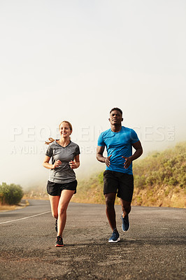 Buy stock photo Shot of two sporty young people out for a run together