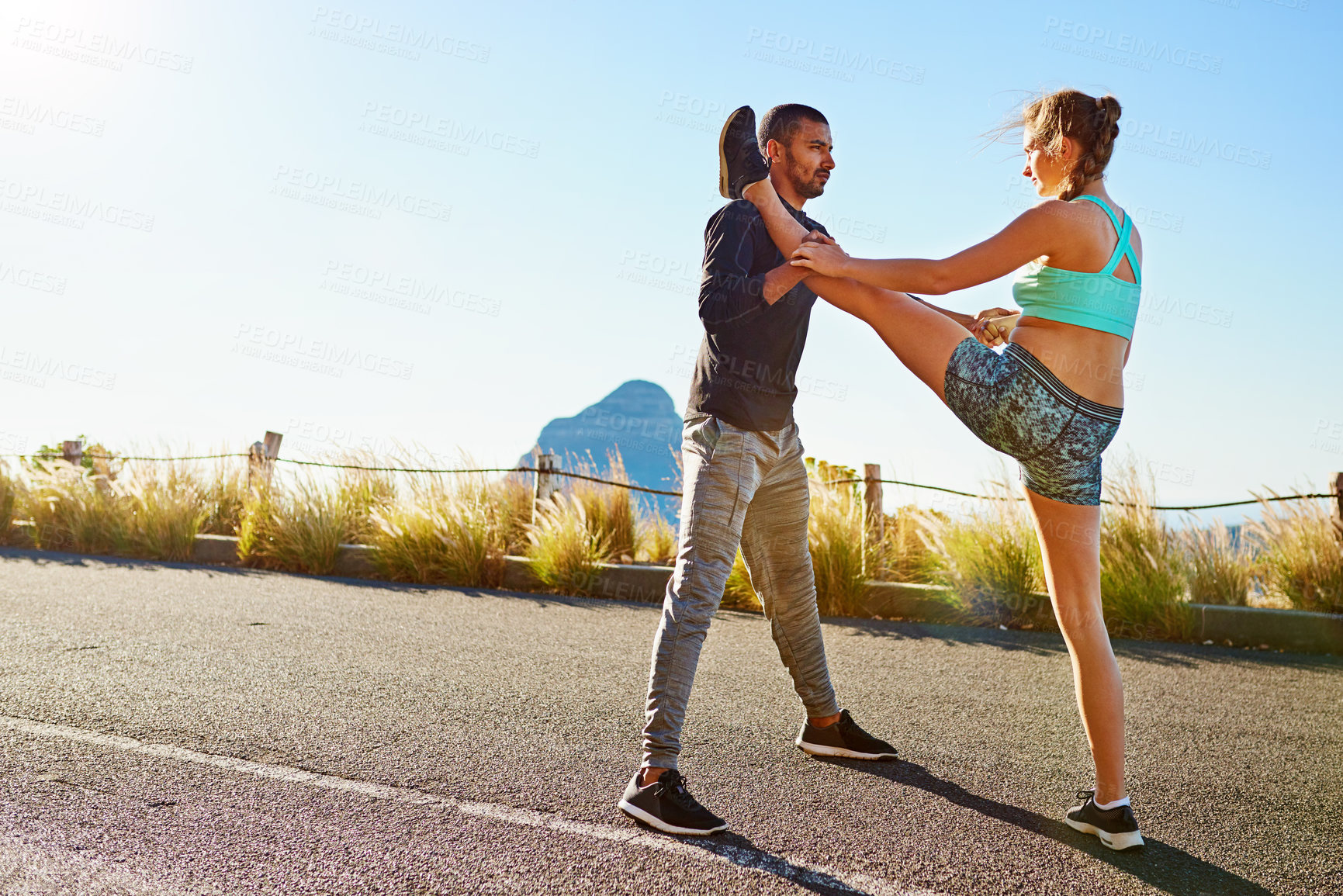 Buy stock photo Fitness, man and woman in nature stretching legs with support, coaching and morning body training together. Warm up, athlete girl and personal trainer on mountain for help with outdoor muscle workout