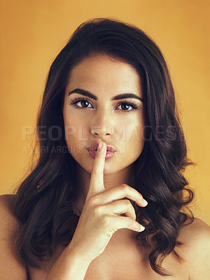 Buy stock photo Shot of a beautiful woman posing with her finger on her lips against a yellow background