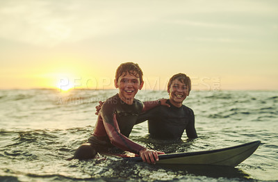 Buy stock photo Portrait of two young brothers sitting on their surfboards in the ocean