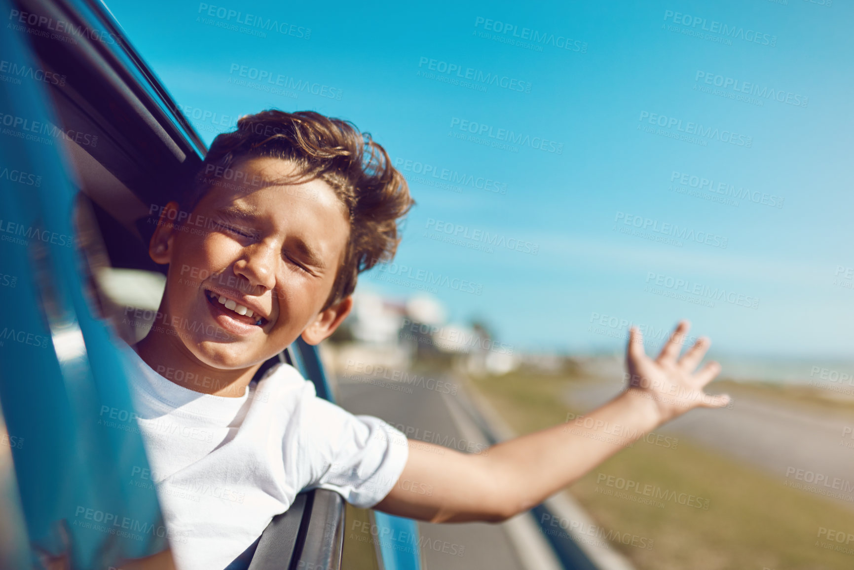 Buy stock photo Shot of a happy young boy leaning out of the car window on a trip to the beach