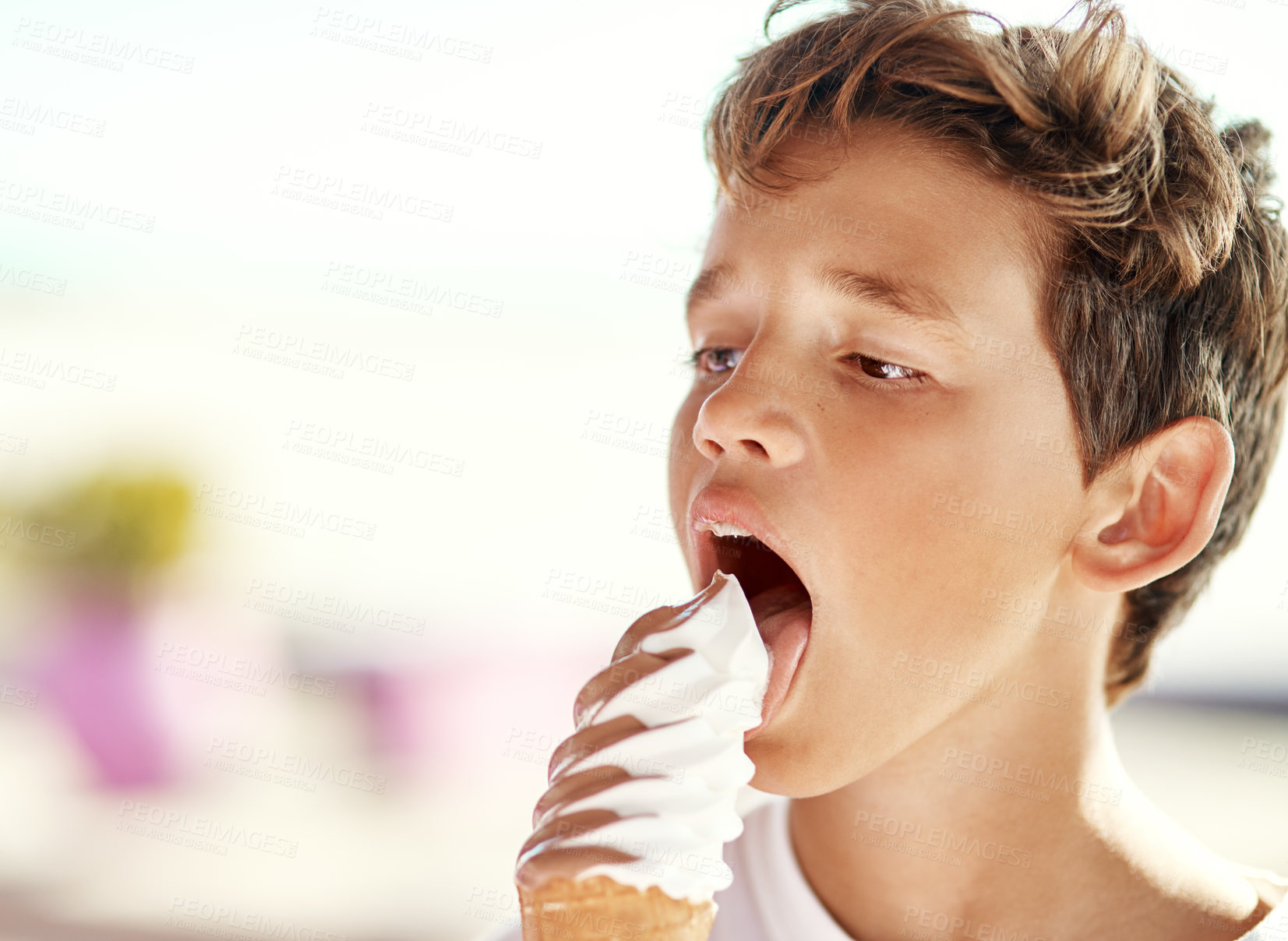 Buy stock photo Shot of a cheerful little boy eating a big ice-cream on his own at the beach