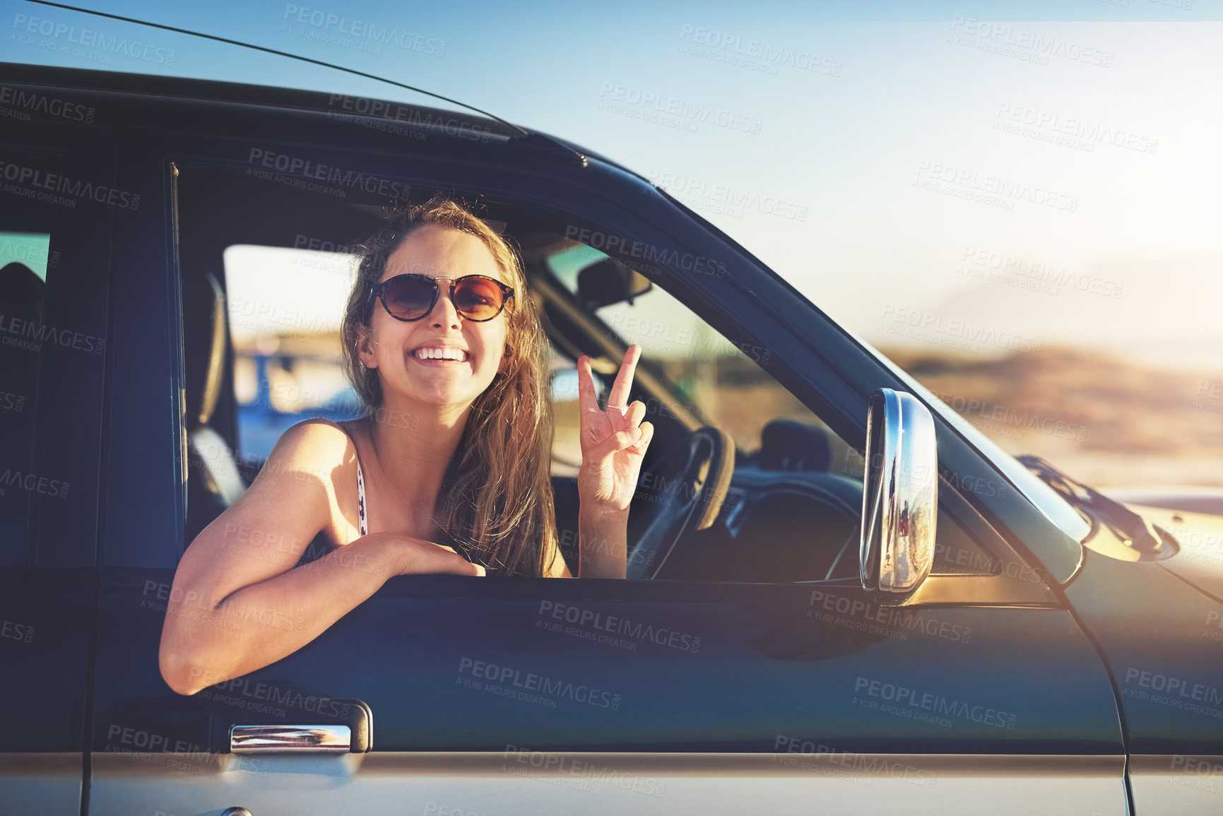 Buy stock photo Cropped portrait of an attractive young woman showing a piece sign while on a roadtrip