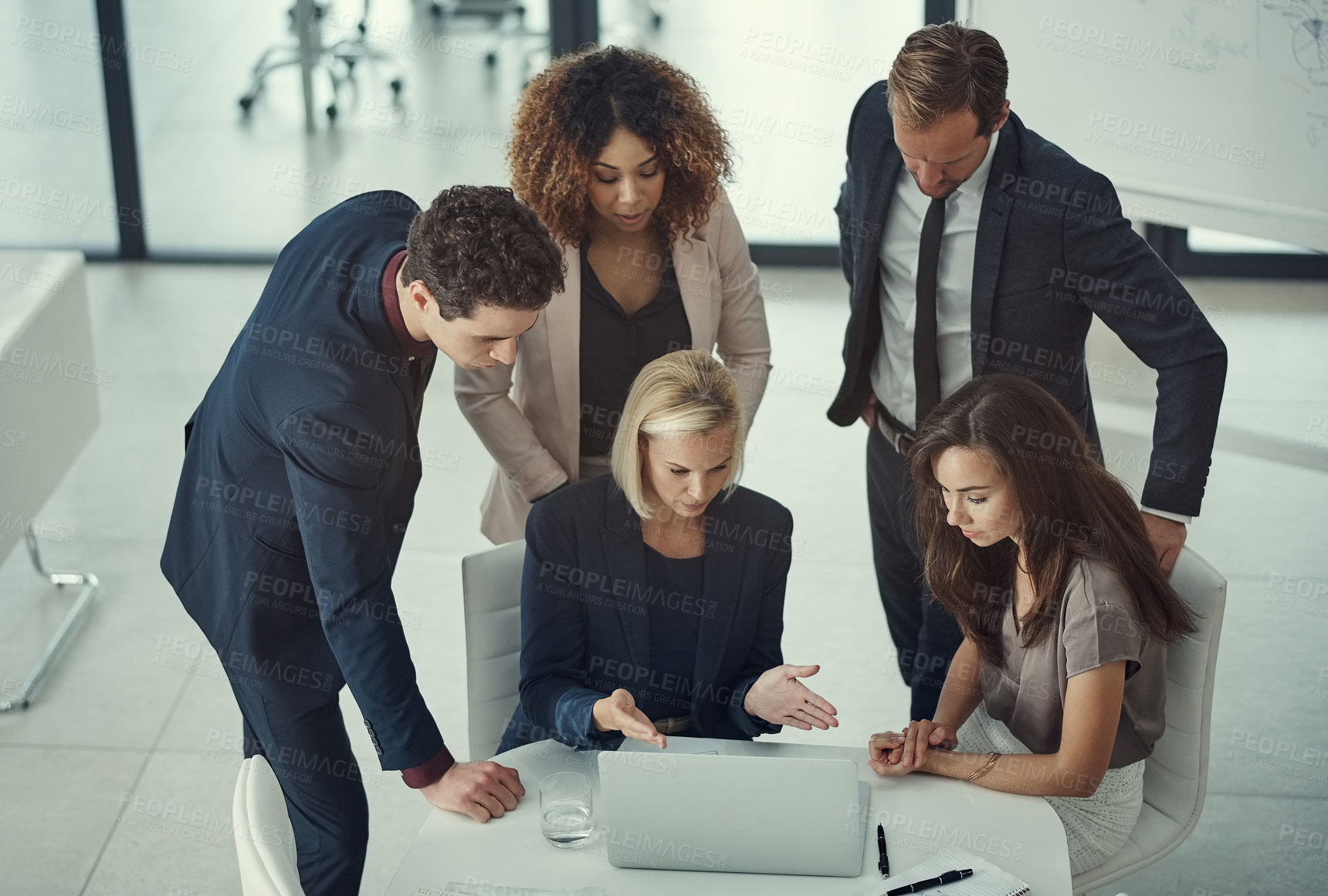 Buy stock photo Shot of a group of colleagues using laptop together during a meeting in a modern office