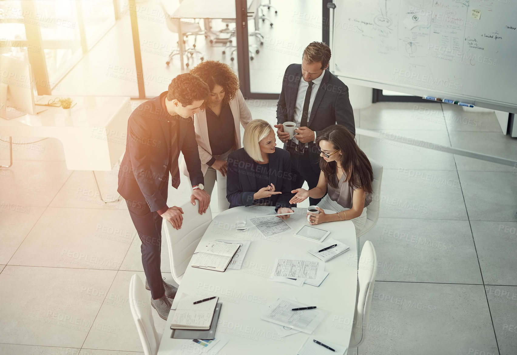 Buy stock photo Shot of a group of colleagues using digital tablet together during a meeting in a modern office