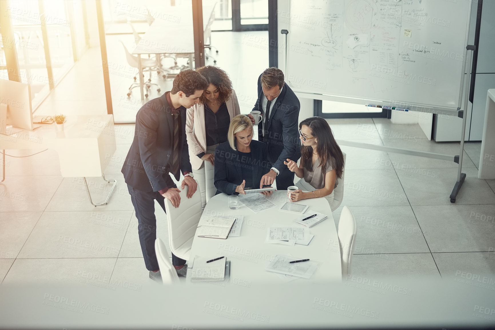 Buy stock photo Shot of a group of colleagues using digital tablet together during a meeting in a modern office