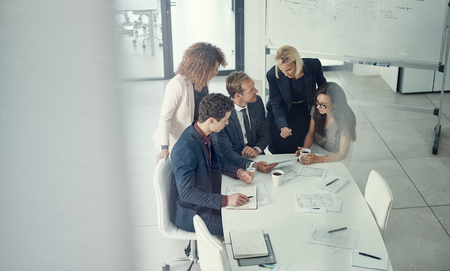 Buy stock photo Shot of a group of colleagues using digital tablet together during a meeting in a modern office