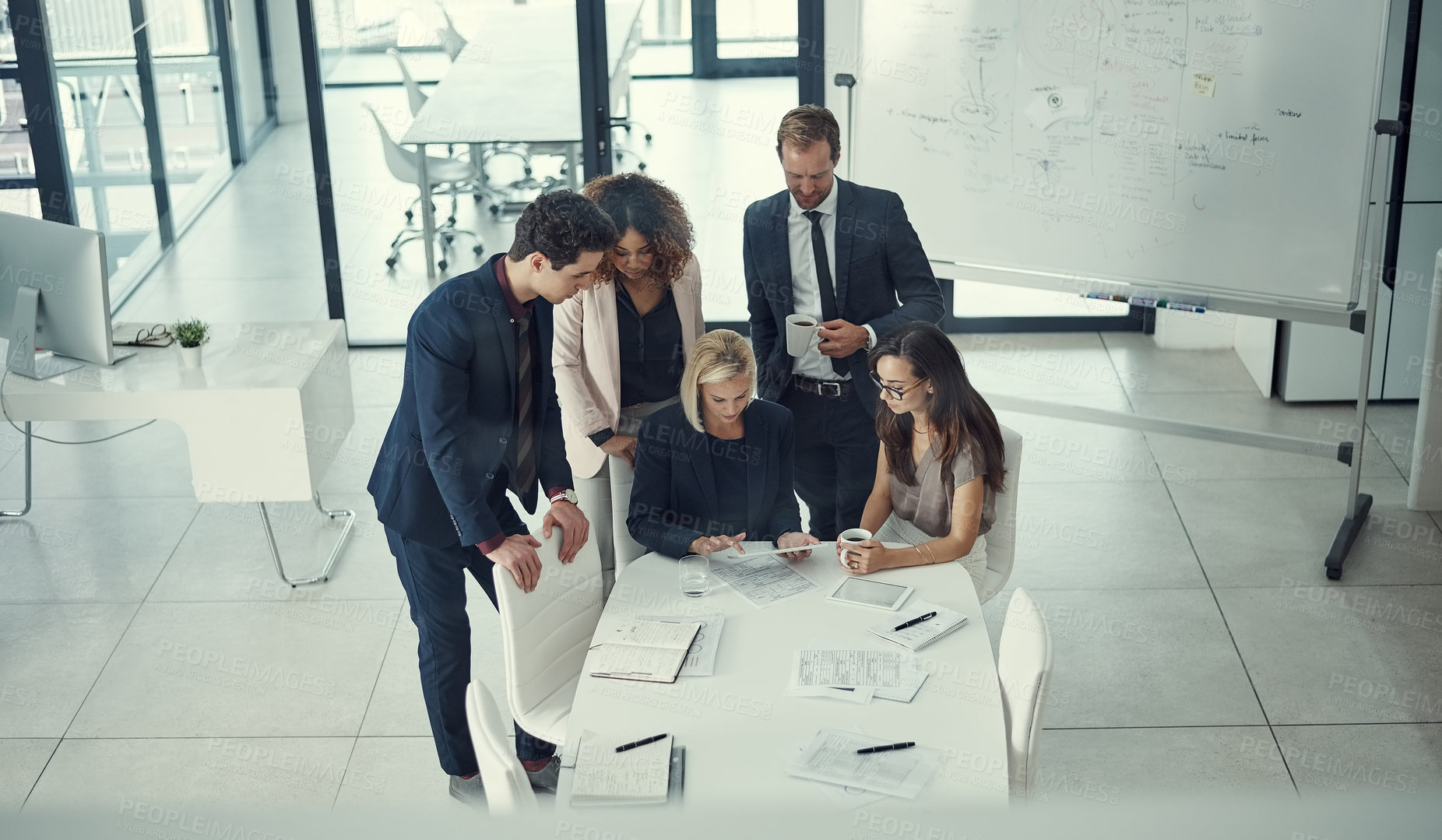 Buy stock photo Shot of a group of colleagues using digital tablet together during a meeting in a modern office