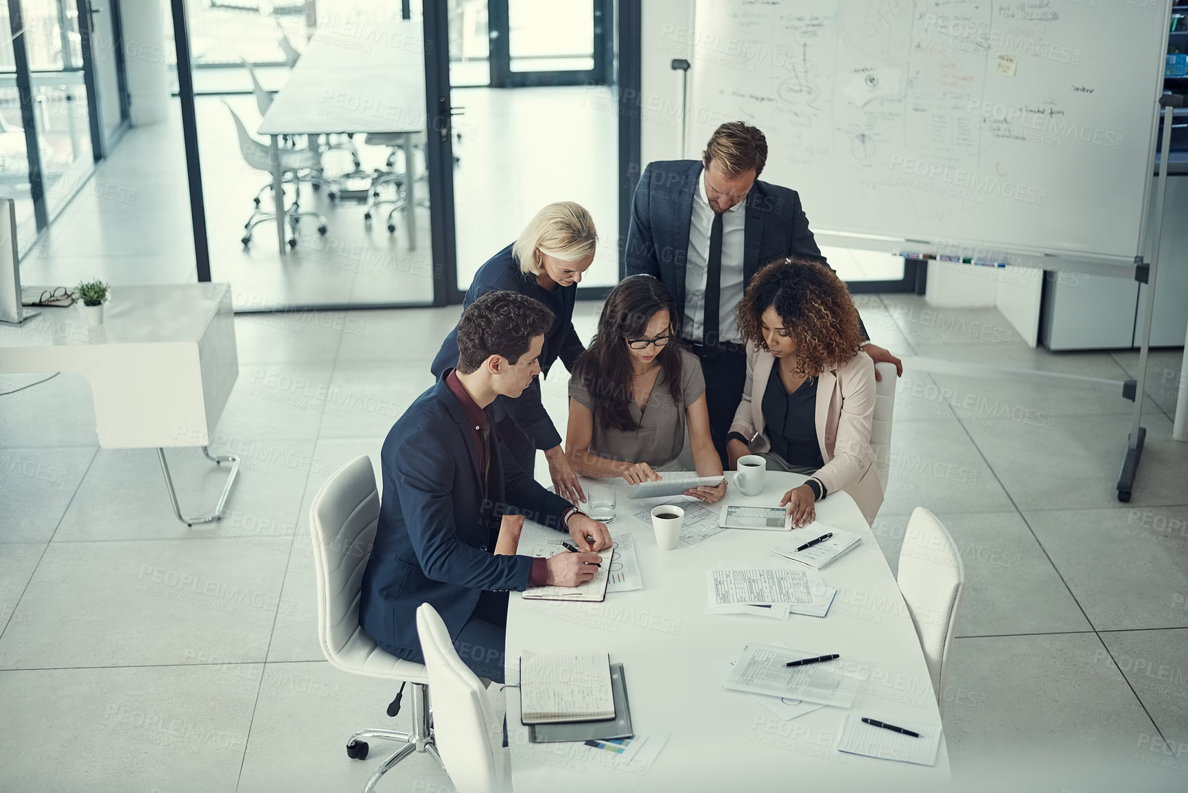 Buy stock photo Shot of a group of colleagues using digital tablet together during a meeting in a modern office