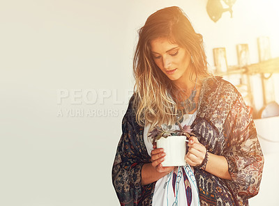 Buy stock photo Shot of a free spirited young woman admiring a pot plant in her hands