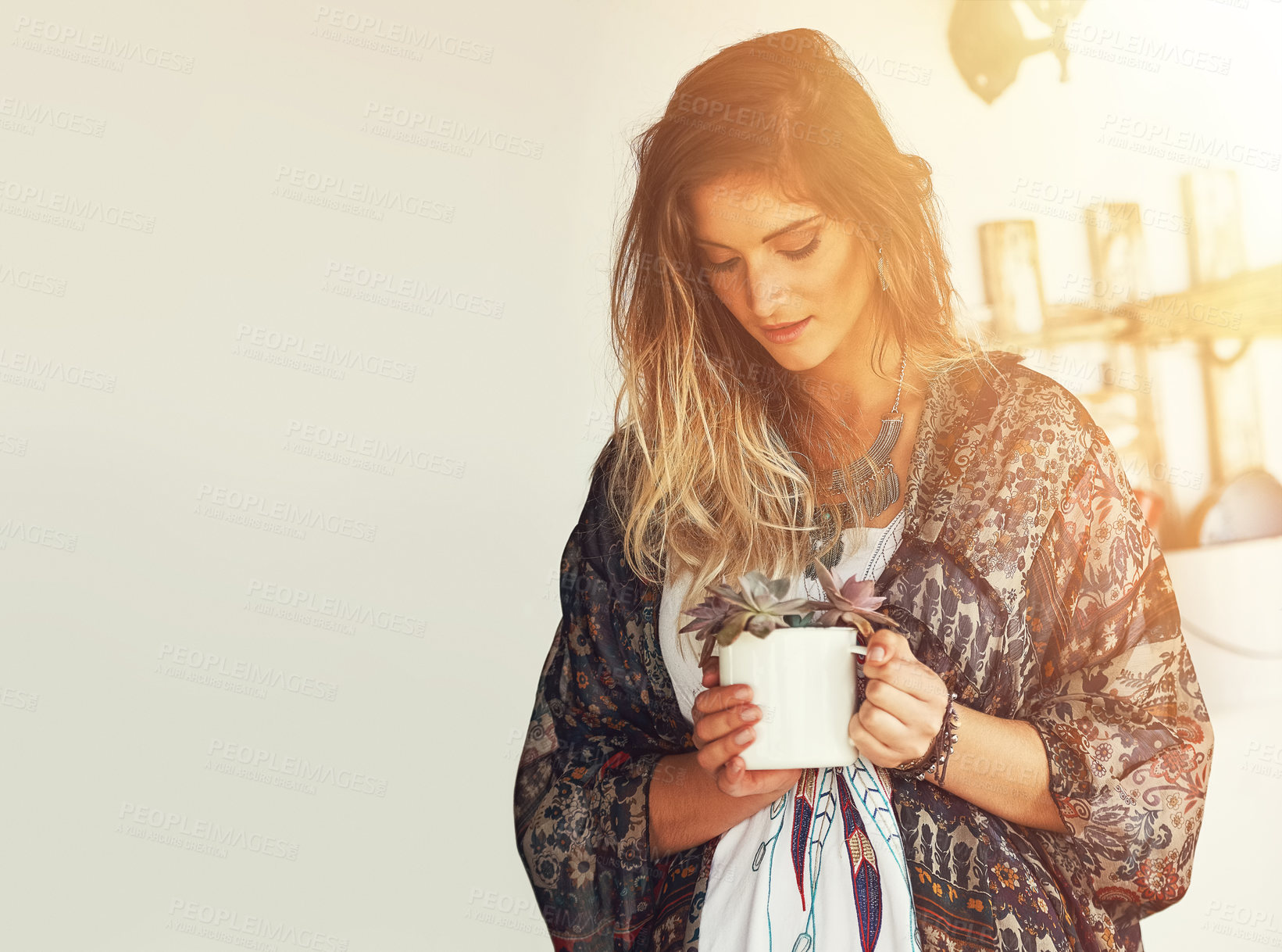 Buy stock photo Shot of a free spirited young woman admiring a pot plant in her hands