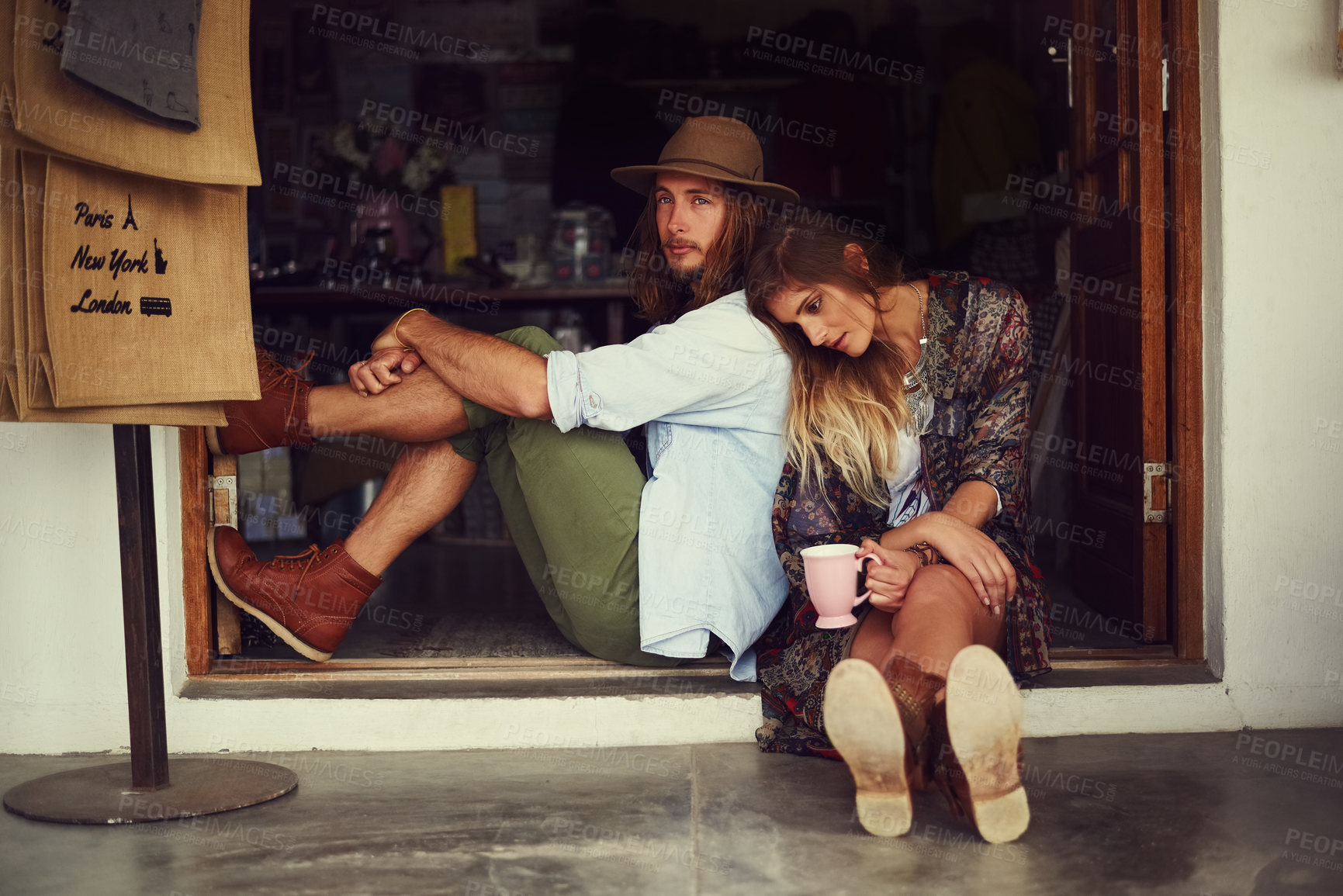 Buy stock photo Shot of an affectionate young couple sitting in the doorway of a roadside shop