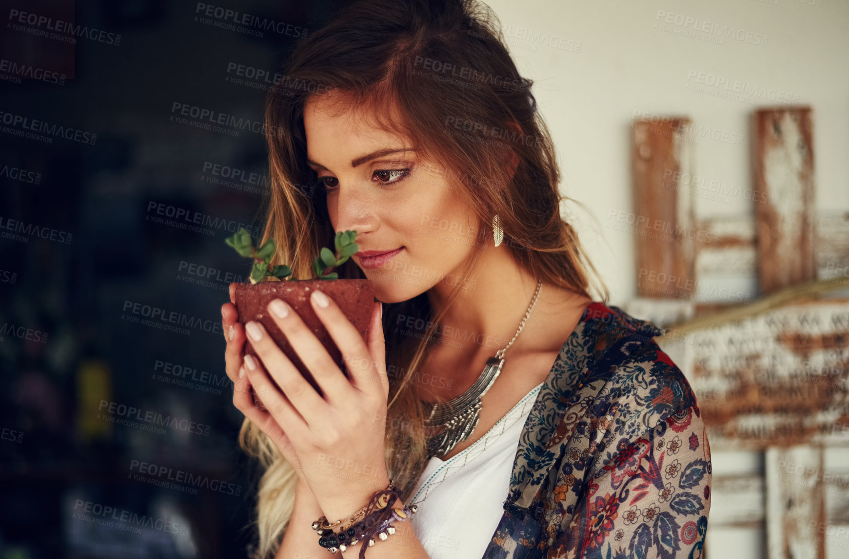 Buy stock photo Shot of a free spirited young woman admiring a pot plant in her hands