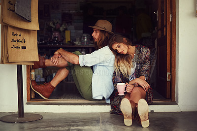 Buy stock photo Shot of an affectionate young couple sitting in the doorway of a roadside shop