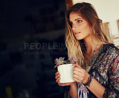 Buy stock photo Shot of a free spirited young woman admiring a pot plant in her hands