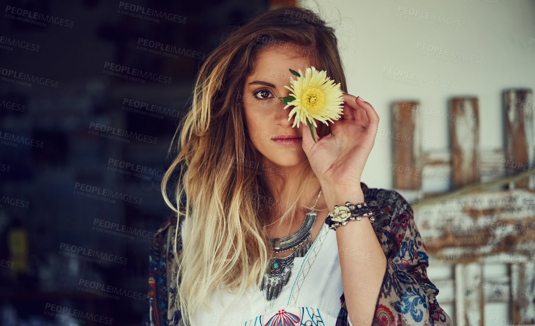 Buy stock photo Portrait of a free spirited young woman posing at a roadside shop with a flower